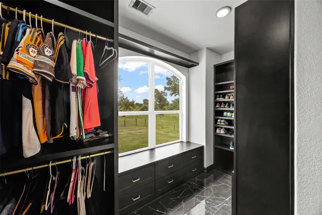 a view of walk in closet with clothes and shoes