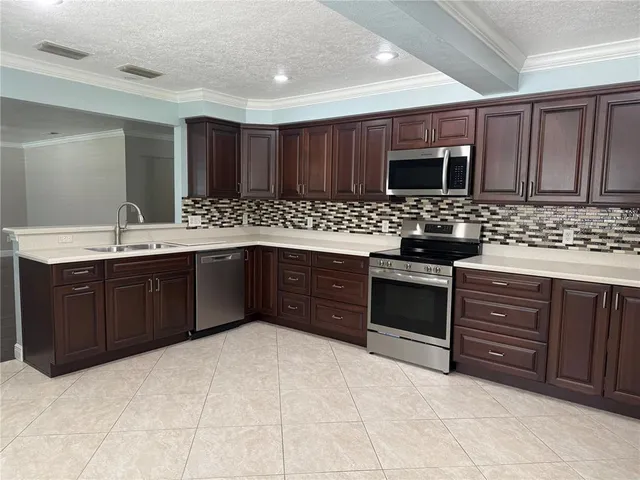 a kitchen with stainless steel appliances granite countertop a stove a sink and a microwave