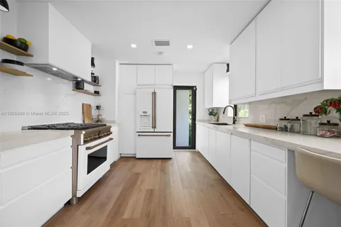 a kitchen with stainless steel appliances a stove a sink and white cabinets with wooden floor