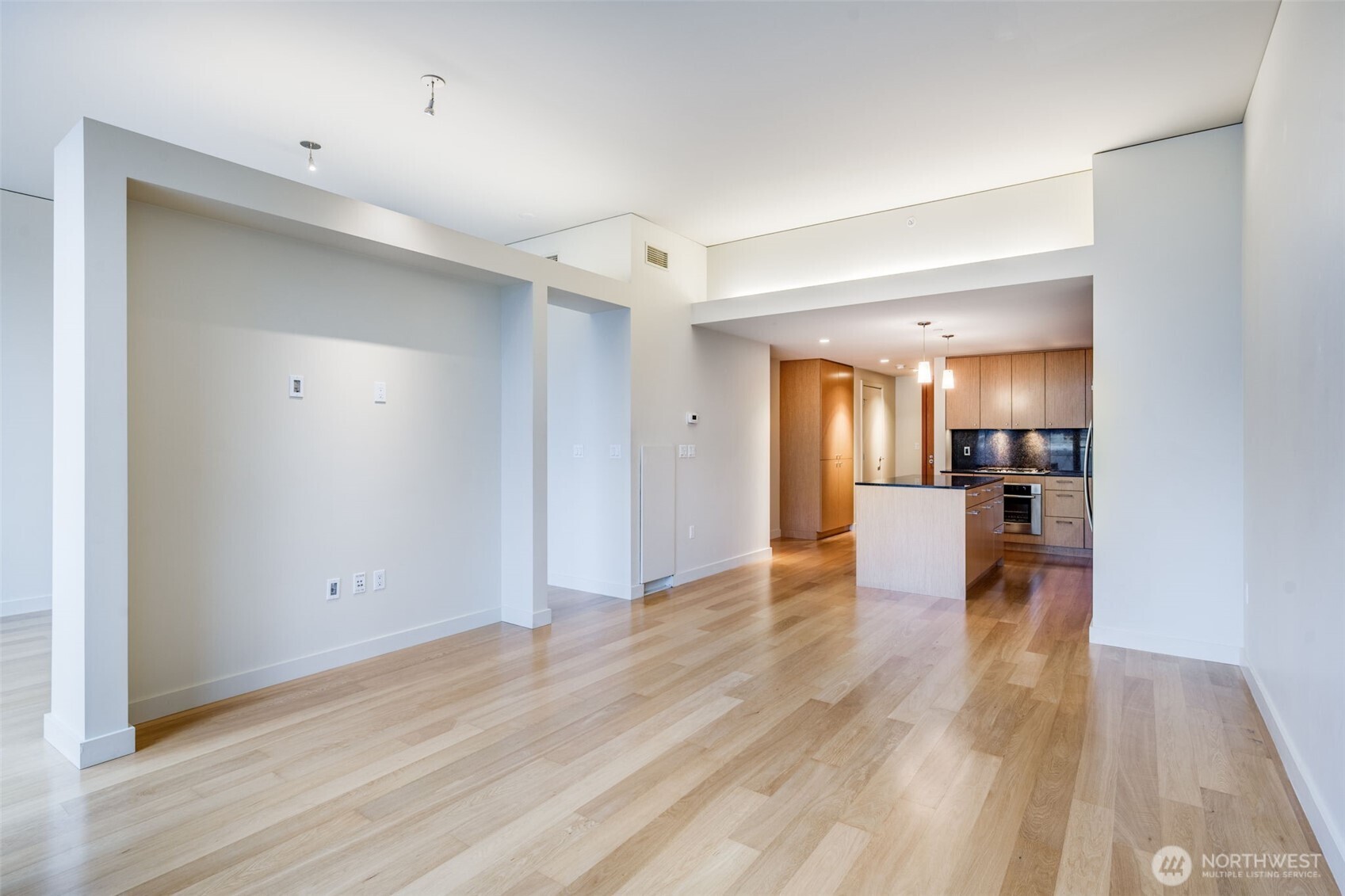909 5th Avenue, Unit 1203 Seattle, WA 98164 - Photo 11 of 32 a view of a hallway with wooden floor and a kitchen