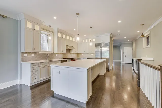 a kitchen with kitchen island a stove a sink a refrigerator and white cabinets