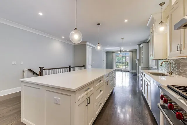 a large white kitchen with a large island oven a stove a sink a island and chairs