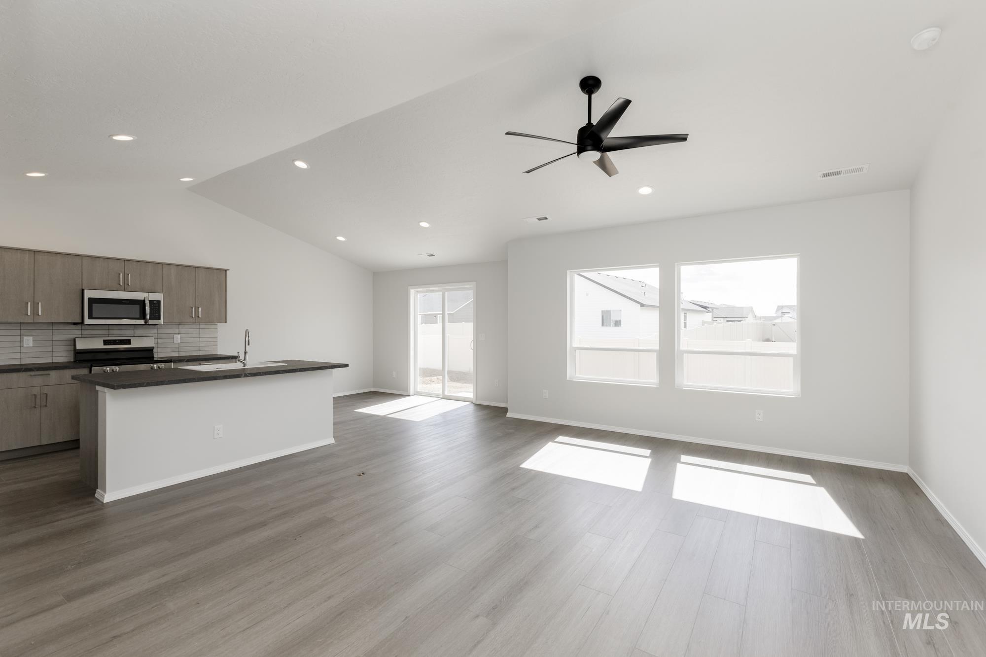 13668 Judson Street Caldwell, ID 83607 - Photo 17 of 17 Kitchen with open floor plan, a center island with sink, decorative backsplash, stainless steel appliances, and a ceiling fan