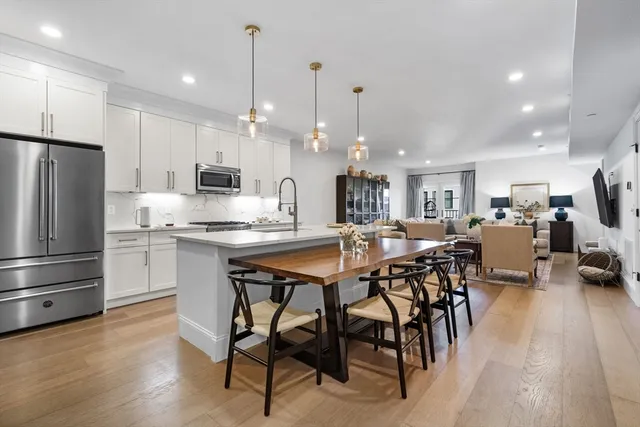 a kitchen with stainless steel appliances kitchen island granite countertop a table chairs and a refrigerator