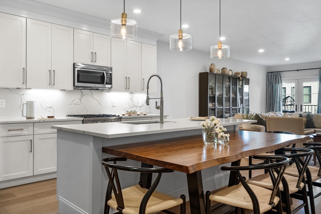 258-260 West 3rd Street, Unit 1 Boston, MA 02127 - Photo 11 of 37 a kitchen with stainless steel appliances granite countertop a stove a refrigerator a microwave a island with white cabinets and wooden floor
