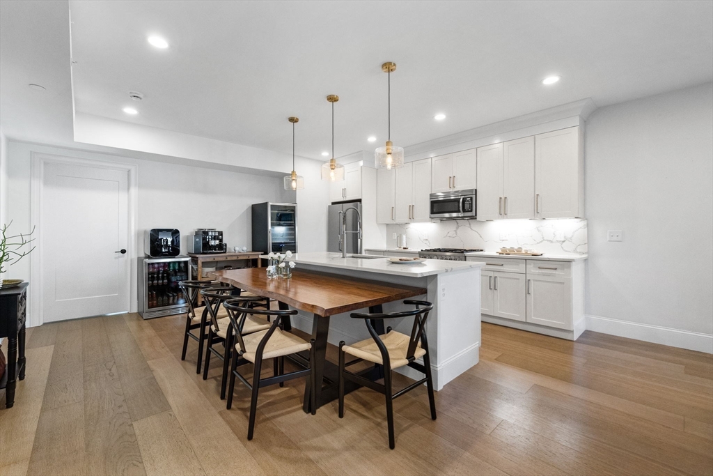 258-260 West 3rd Street, Unit 1 Boston, MA 02127 - Photo 9 of 37 a kitchen with stainless steel appliances kitchen island granite countertop a table chairs sink and cabinets