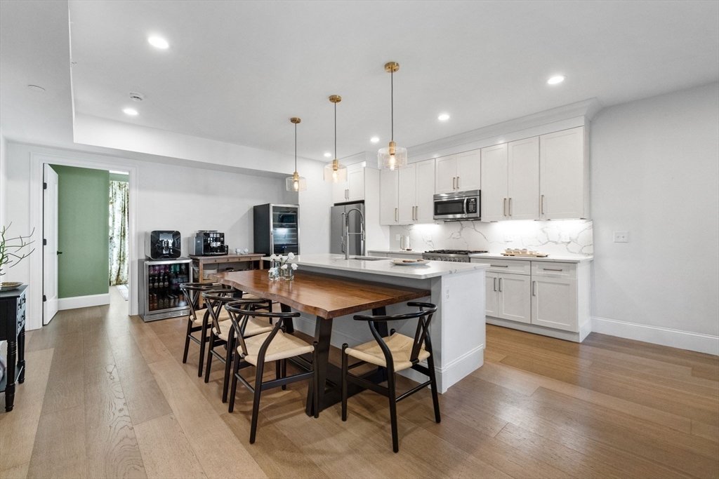 258-260 West 3rd Street, Unit 1 Boston, MA 02127 - Photo 10 of 37 a kitchen with stainless steel appliances kitchen island granite countertop a table chairs and a refrigerator