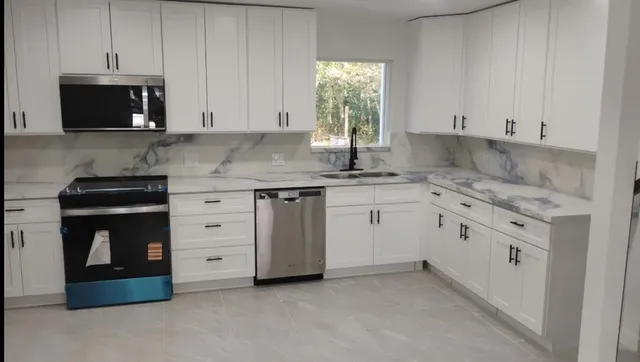 a kitchen with granite countertop white cabinets and stainless steel appliances