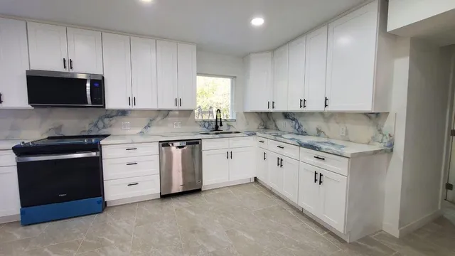 a kitchen with granite countertop white cabinets and stainless steel appliances