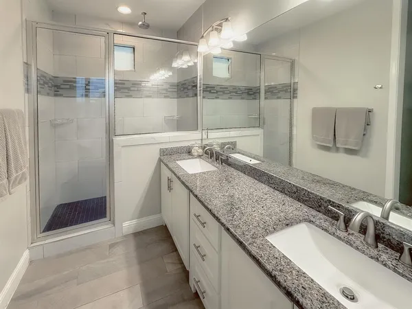 a bathroom with double vanity and a shower