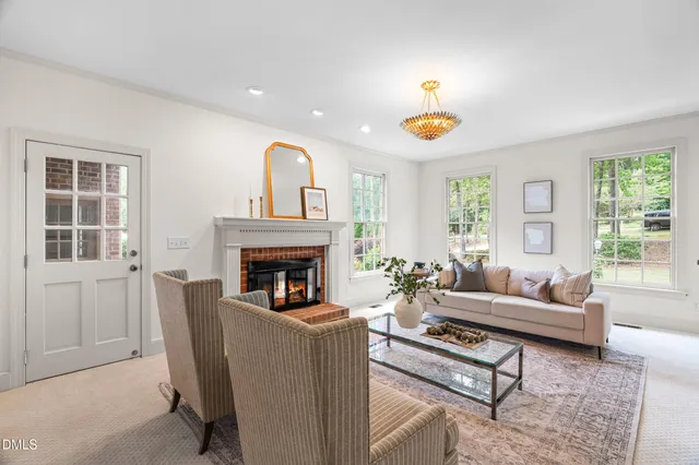 a living room with fireplace a chandelier and a table