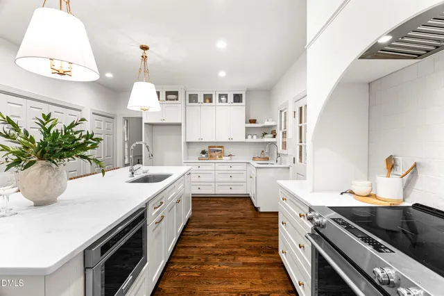 a kitchen with kitchen island granite countertop a stove a sink a island and chairs in it