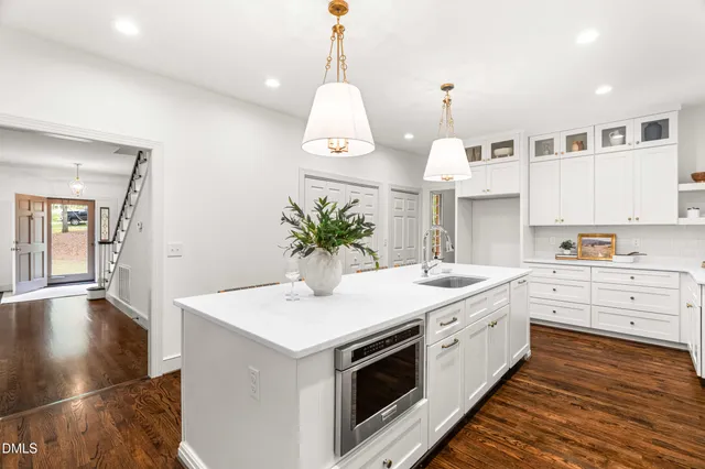 a kitchen with granite countertop a white stove top oven and white cabinets with wooden floor