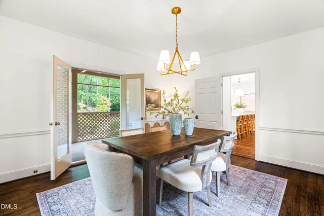 a dining room with chandelier and wooden floor