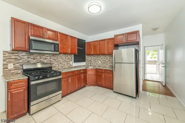 a kitchen with a refrigerator a stove top oven and cabinets