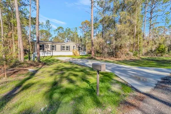 a view of a house with a small yard and large trees