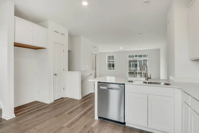 a kitchen with stainless steel appliances white cabinets and wooden floors