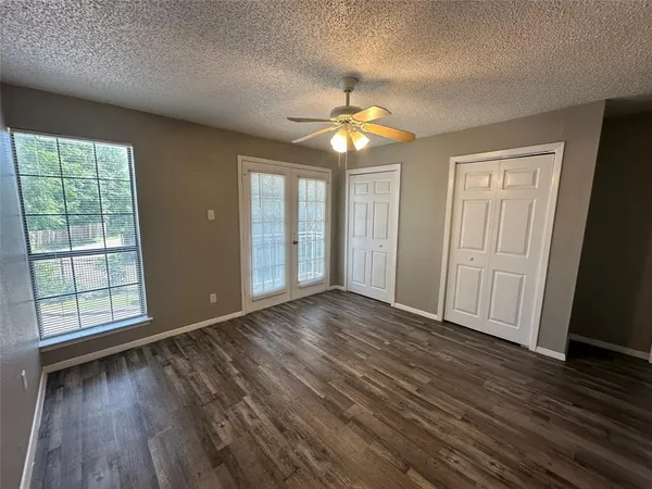 an empty room with wooden floor and chandelier fan