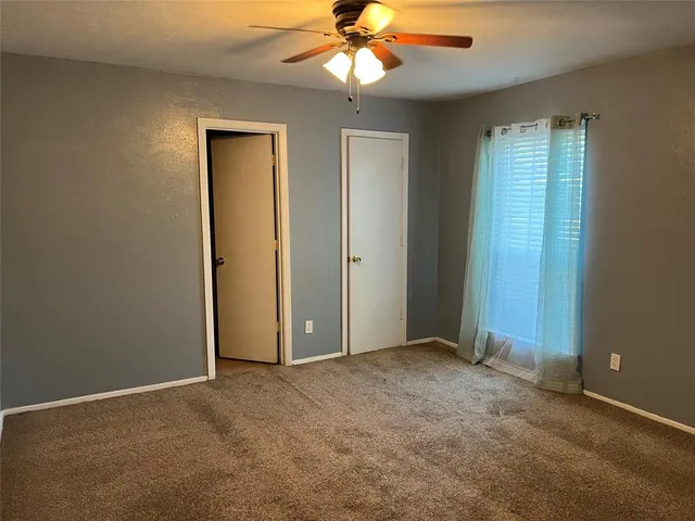 an empty room with a chandelier fan and a window