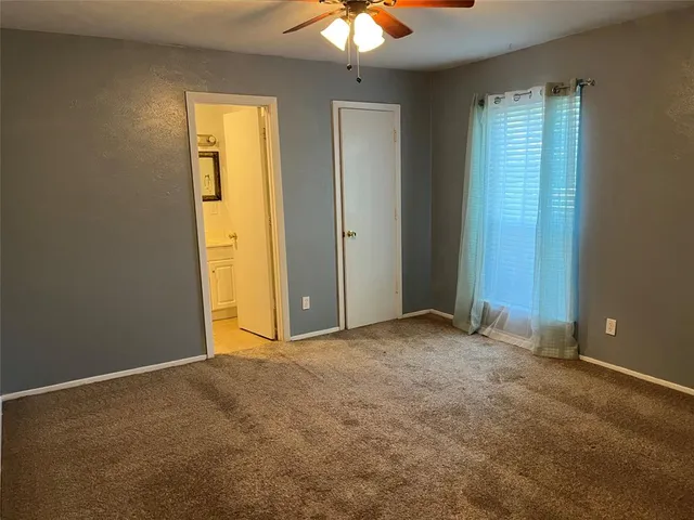 an empty room with a chandelier fan and closet
