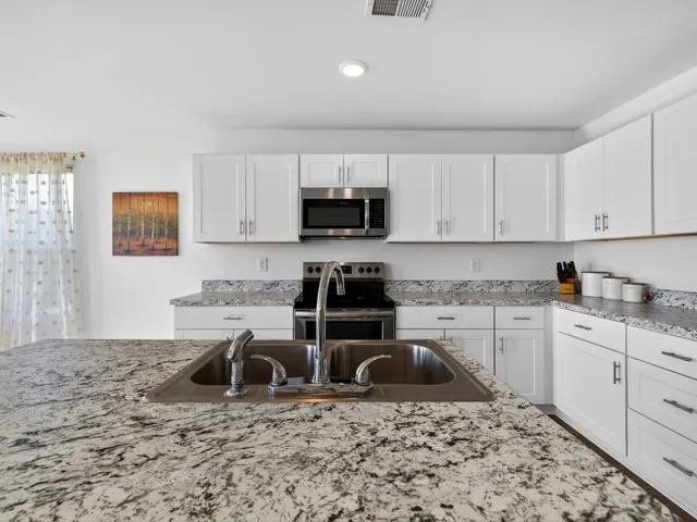 a kitchen with a stove a sink a microwave and cabinets
