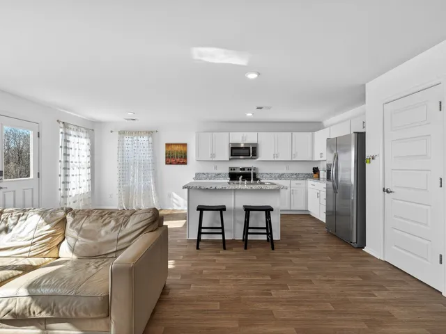 a living room with stainless steel appliances kitchen island granite countertop furniture and a couch