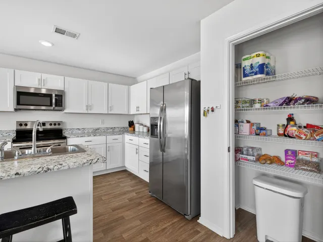 a kitchen with granite countertop a refrigerator and a stove top oven
