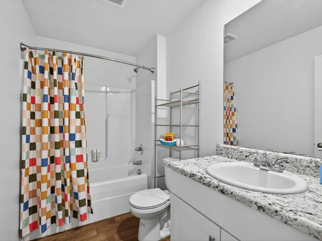 a bathroom with a granite countertop sink toilet and shower