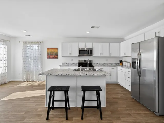 a kitchen with stainless steel appliances granite countertop a white cabinets and a refrigerator