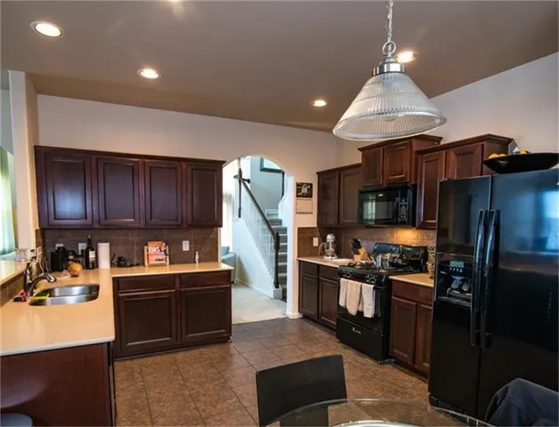 a kitchen with stainless steel appliances granite countertop a stove refrigerator and a sink