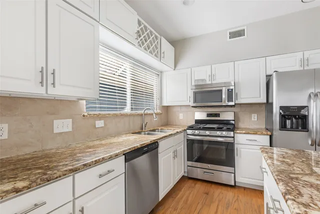 a kitchen with stainless steel appliances granite countertop a stove a sink and a microwave