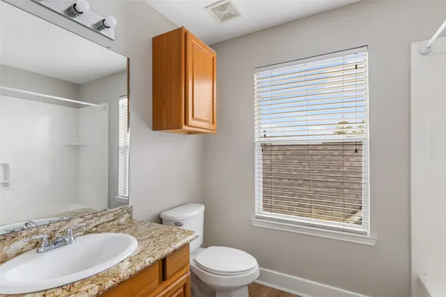 a bathroom with a granite countertop sink toilet a mirror and shower