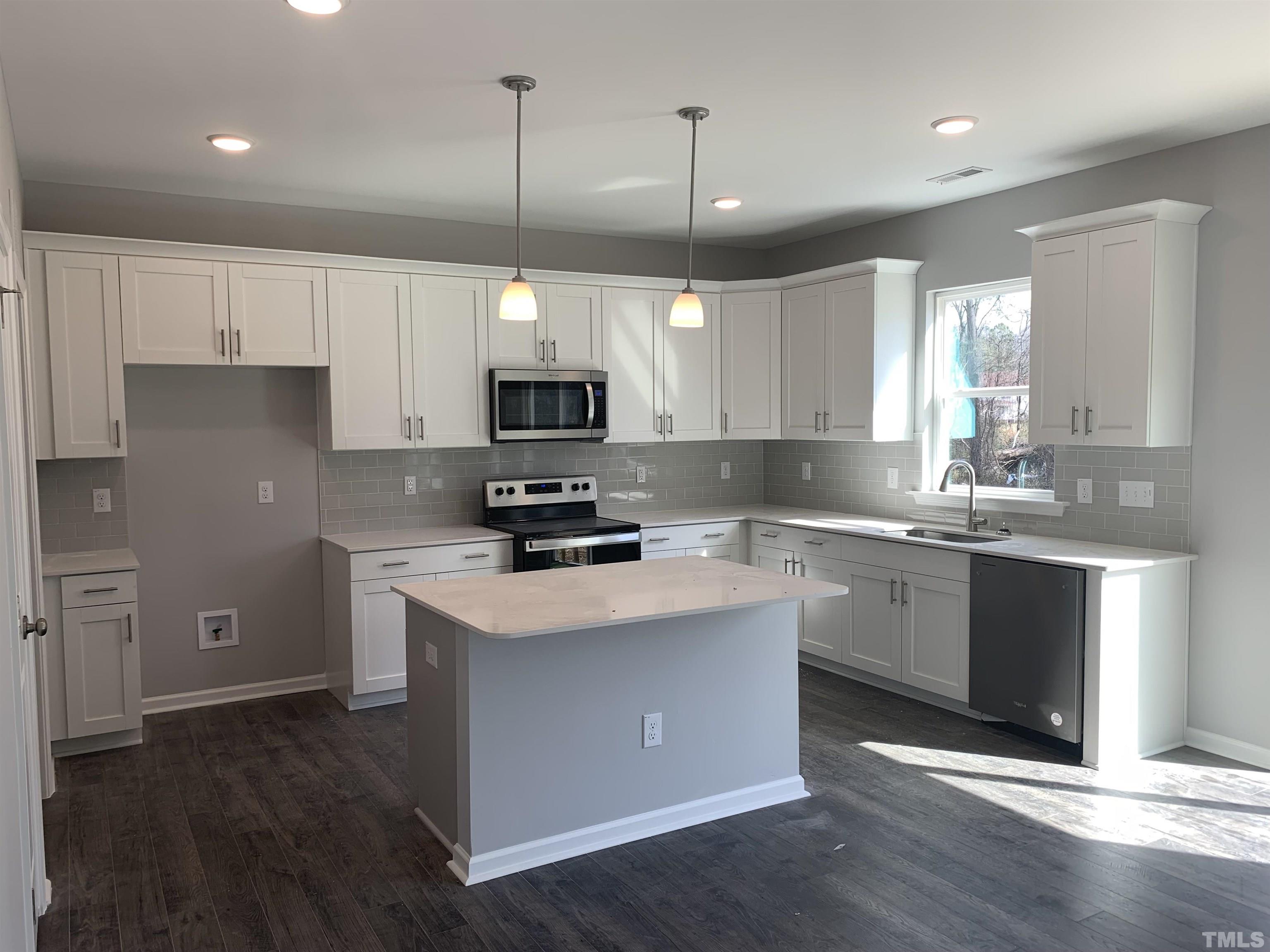 32 Daffodil Garden Court Smithfield, NC 27577 - Photo 6 of 19 a kitchen with kitchen island granite countertop a sink a counter space appliances and cabinets
