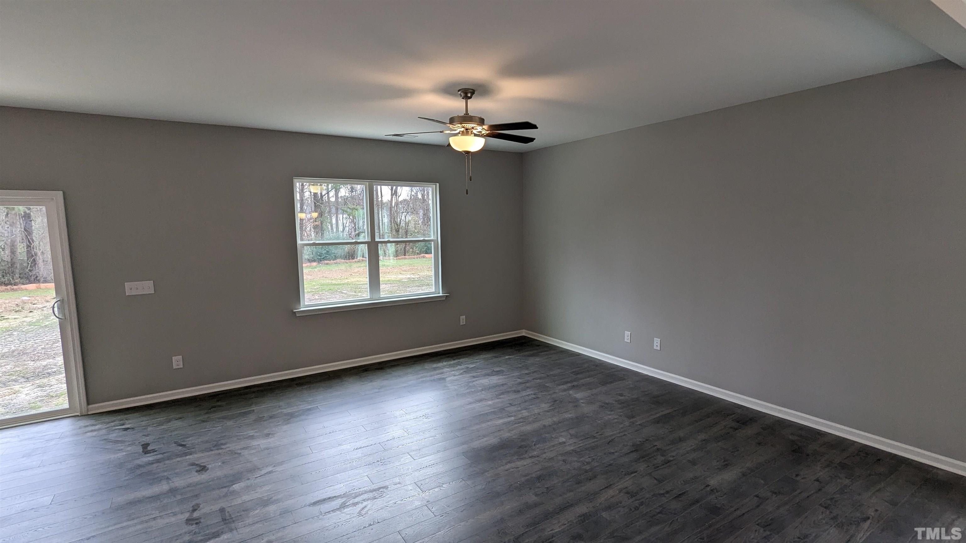 32 Daffodil Garden Court Smithfield, NC 27577 - Photo 8 of 19 an empty room with wooden floor chandelier fan and windows
