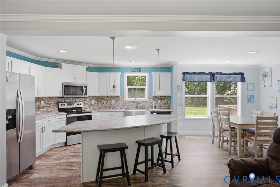 93 Faraway Road Saluda, VA 23149 - Photo 13 of 58 a kitchen with stainless steel appliances granite countertop a stove a refrigerator a kitchen island a dining table and chairs with wooden floor