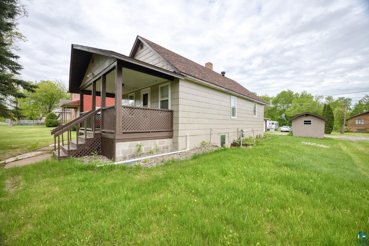 4191 Kerr Location Hibbing, MN 55746 - Photo 26 of 37 View of side of property with a lawn, a chimney, roof with shingles, and a porch