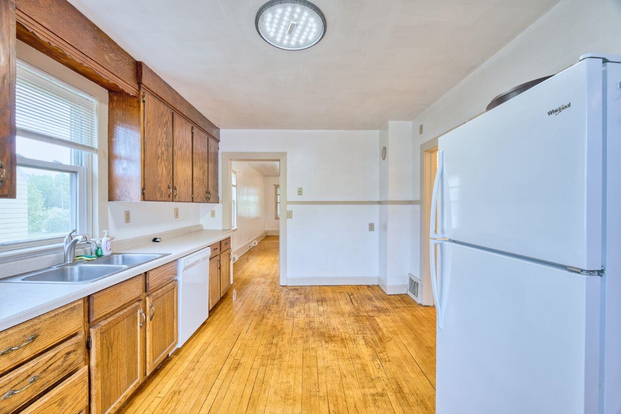 4191 Kerr Location Hibbing, MN 55746 - Photo 7 of 37 Kitchen with white appliances, a sink, light wood finished floors, light countertops, and brown cabinetry