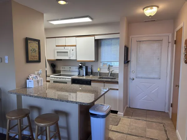 a kitchen with kitchen island granite countertop a sink cabinets and refrigerator