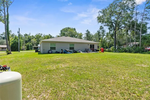 a white house with a big yard and large trees