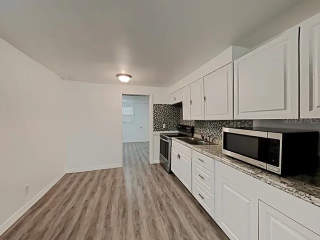 a kitchen with granite countertop white cabinets and white appliances