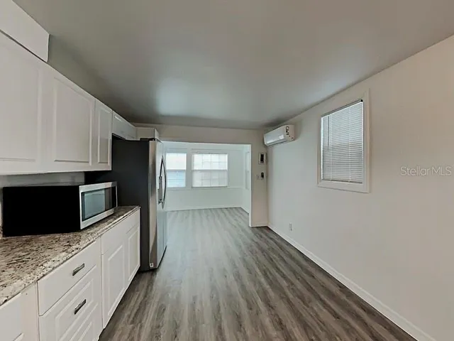a kitchen with granite countertop white cabinets and wooden floor