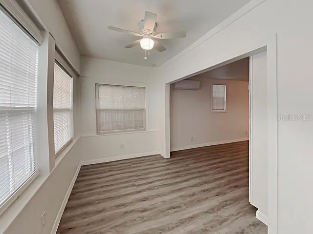 a view of an empty room with wooden floor and a window