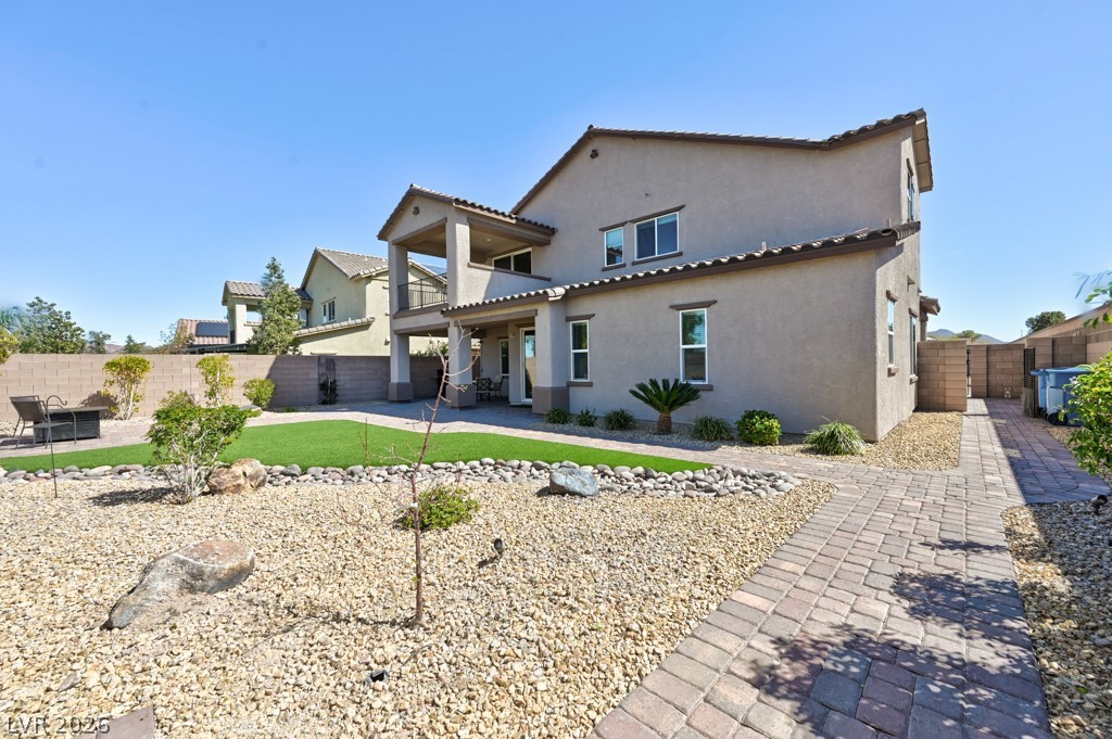 1054 Langston Ranch Avenue Henderson, NV 89002 - Photo 11 of 82 Rear view of house featuring a fenced backyard, stucco exterior, a balcony, patio areas and a gate leading to front driveway. Very large 8712 SF lot.