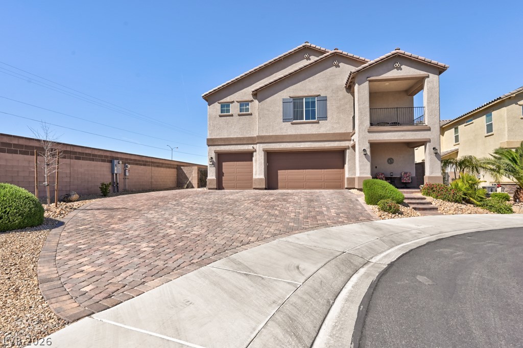 1054 Langston Ranch Avenue Henderson, NV 89002 - Photo 2 of 82 View of front of property with a garage, a balcony, stucco siding, and decorative driveway. Left Side gate leads to Casita entrance.