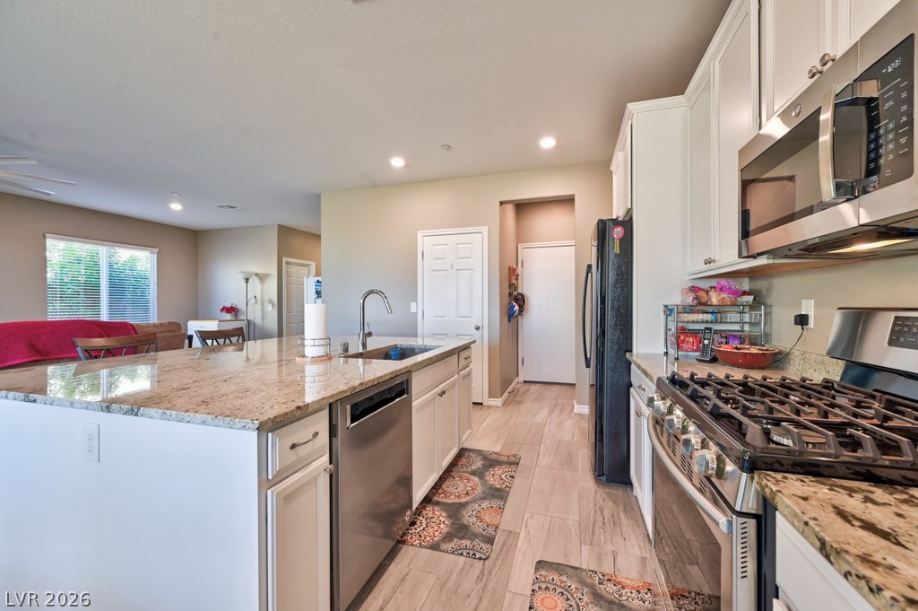 1054 Langston Ranch Avenue Henderson, NV 89002 - Photo 24 of 82 Kitchen featuring stainless steel & black appliances, a kitchen island with sink, white cabinetry, light granite counters and recessed lighting