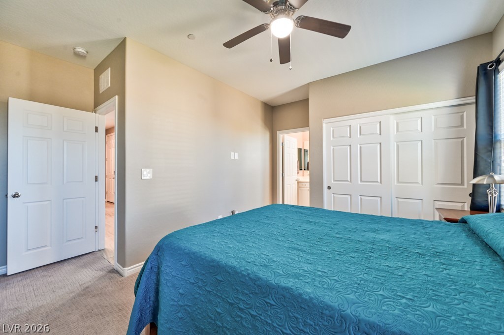 1054 Langston Ranch Avenue Henderson, NV 89002 - Photo 31 of 82 CASITA Bedroom different angle with light carpet, a ceiling fan, a closet, and connected bathroom.