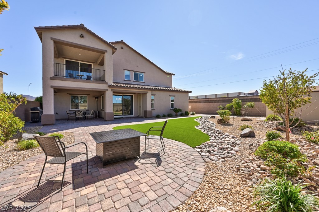 1054 Langston Ranch Avenue Henderson, NV 89002 - Photo 5 of 82 Back of property with a Covered patio with outdoor dining area, a balcony that faces North, stucco exterior, fully fenced back yard with a block wall and a fire pit area. Luscious green faux turf and low maintenance decorative xeriscape.