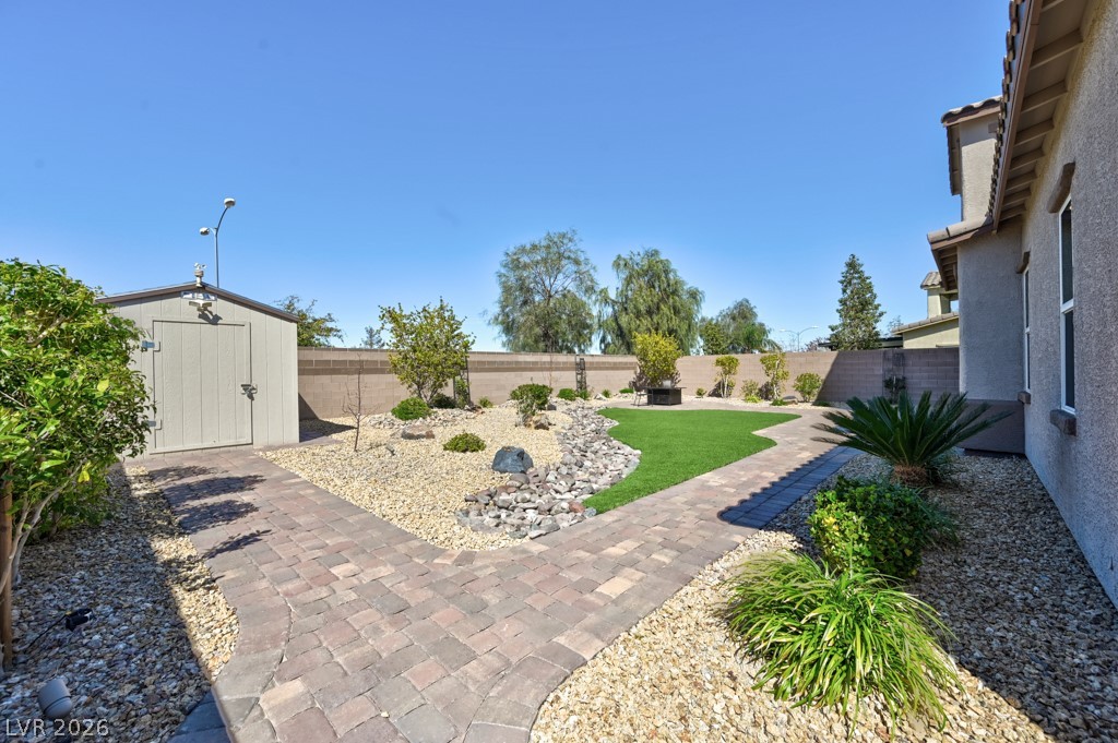 1054 Langston Ranch Avenue Henderson, NV 89002 - Photo 10 of 82 Fenced backyard with a storage shed. Extensive paver stones throughout the property creating interest. $$$$$$$ in UPGRADES. Lush green landscaping.