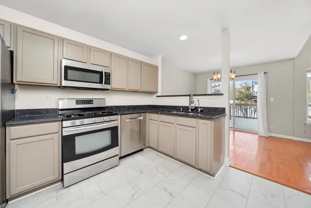 a kitchen with stainless steel appliances granite countertop a sink and a stove top oven with white cabinets
