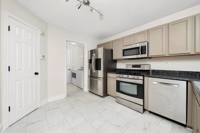 a kitchen with stainless steel appliances granite countertop a refrigerator and a stove top oven